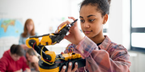 College student holding her robotic toy at robotics classroom at school.