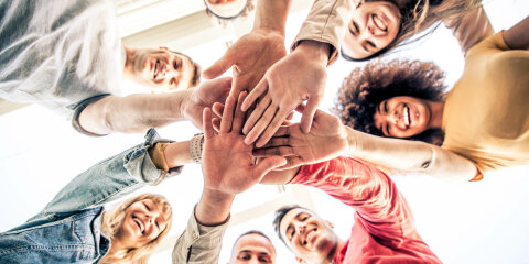 Young happy people stacking hands together outcoor - Community of multiracial international people supporting each other - Diverse culture
