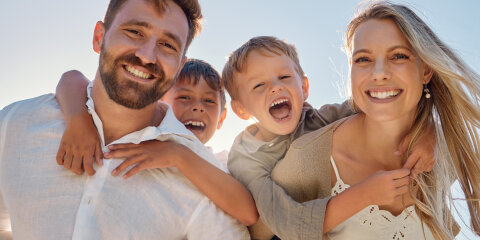 Happy family, portrait and beach with happy, smile and relax mother and father hug, embrace and laughing together. Kids, face and parents on sea vacation with family bonding, excited and cheerful