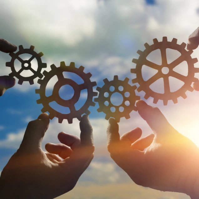 Four hands of businessmen collect from the gears of the details of puzzles. against the background of sunlight. The concept of a business idea. Teamwork. strategy. cooperation